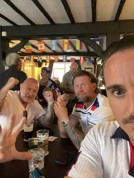England supporters gathered around a table in a busy village pub decorated with international flags